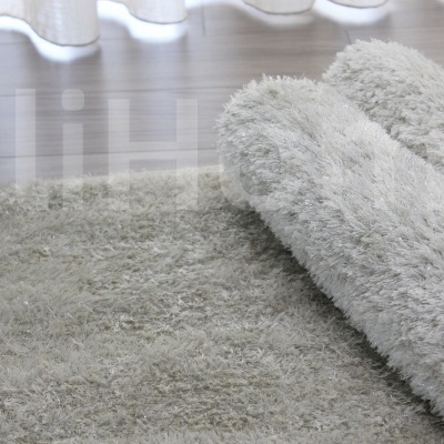 Tapete felpudo cinza claro sobre chão de madeira clara