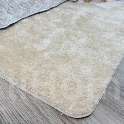 Tapete bege peludo colocado em piso castanho claro
