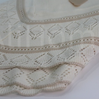 Pano de tecido branco com padrão bordado de losangos e linhas, acabamento ondulado