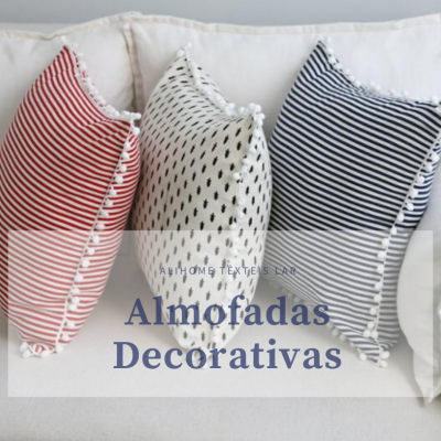 Três almofadas decorativas com padrões em riscas e pontos sobre sofá branco