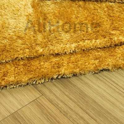 Tapete felpudo castanho dourado sobre chão de madeira clara