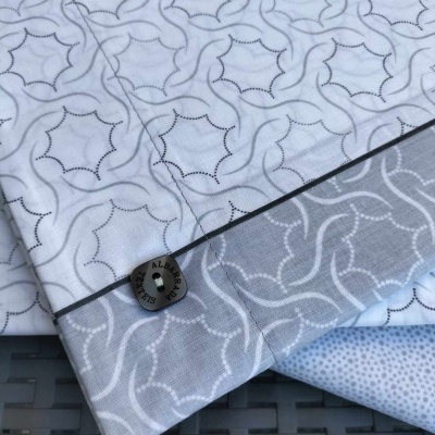 Conjunto de roupa de cama com padrões geométricos e etiqueta ALBA SISA