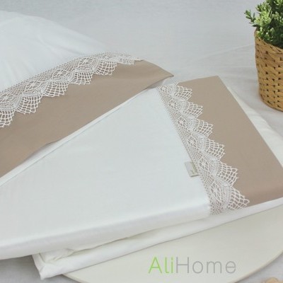 Conjunto de roupa de cama branca com renda bege e vaso de planta em cesta de vime