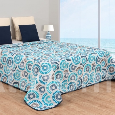Colcha com padrão circular azul e bege num quarto com vista para o mar