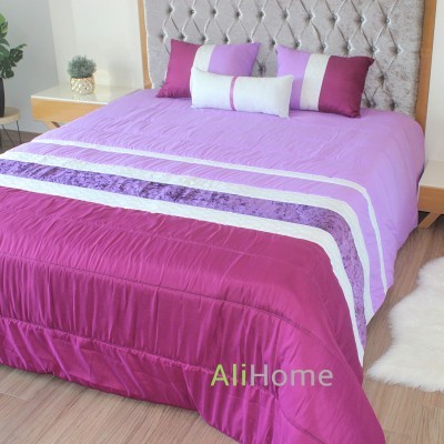 Colcha e almofadas em tons de roxo e lilás numa cama com cabeceira estofada