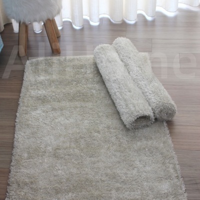 Tapete felpudo bege claro com dois tapetes enrolados e banco com almofada branca felpuda