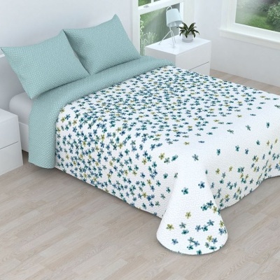 Cama de casal com roupa de cama azul claro e edredão branco com flores azuis e amarelas num quarto moderno