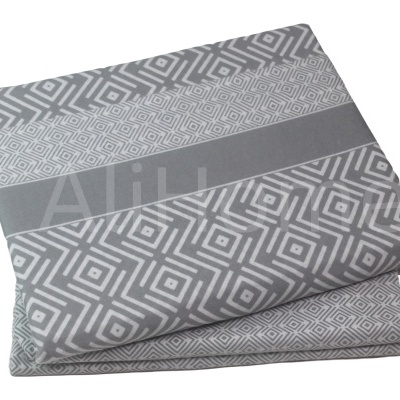 Conjunto de roupa de cama dobrada em padrões geométricos cinza e branco.