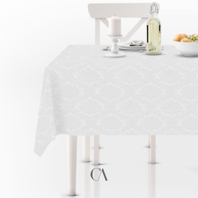 Toalha de mesa branca com padrão floral texturizado numa mesa branca com cadeira ao fundo