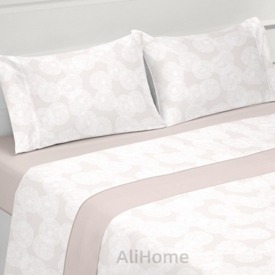 Jogo de cama branco com padrão de círculos, incluindo duas fronhas e um lençol, em cama com estrutura branca