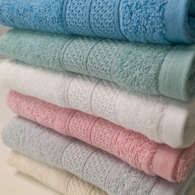 Toalhas empilhadas em várias cores com textura felpuda e faixa decorativa