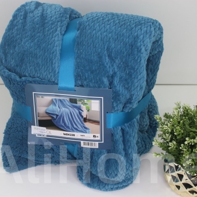 Manta azul texturizada com etiqueta e planta em vaso dourado