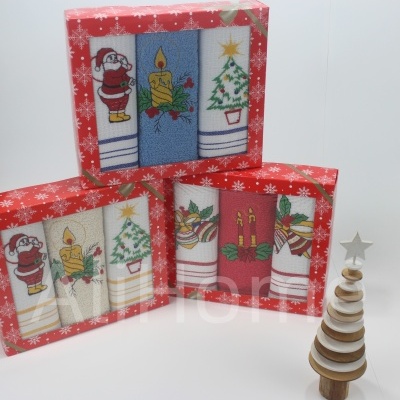 Conjuntos de toalhas de cozinha natalícias em embalagens vermelhas e ornamento de árvore de natal de madeira.