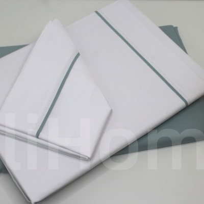 Conjunto de roupa de cama branca com riscas cinza e capa cinza sobre superfície branca com planta decorativa