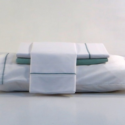 Conjunto de roupa de cama branca com linhas finas azuis e lençóis sobre almofada branca