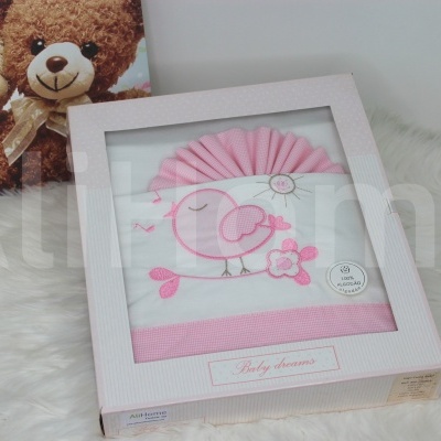 Caixa branca com toalha bordada branca e rosa com pássaro em fundo peludo branco