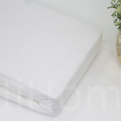 Lençol branco com vaso dourado e planta verde ao lado