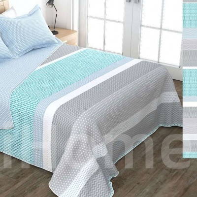 Cama com roupa de cama reversível azul, cinza e branco com padrões de listras e pontos brancos