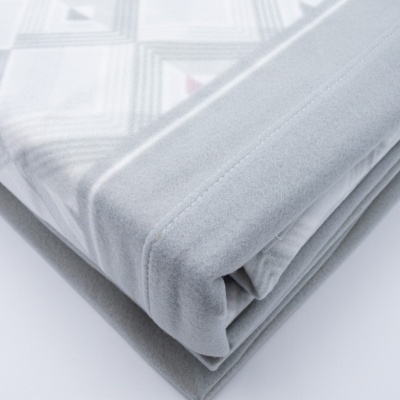 Manta cinza com padrão geométrico dobrada