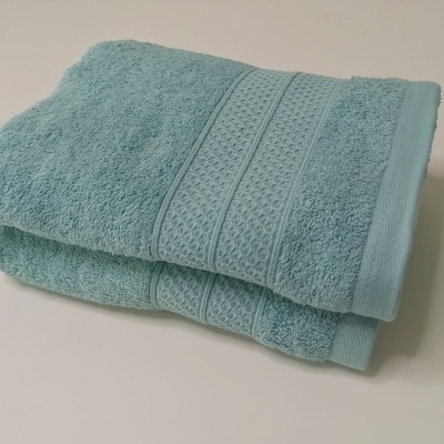 Toalhas de banho azuis claras dobradas com faixa decorativa