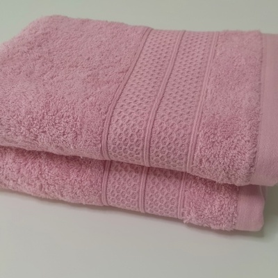 Toalhas de banho cor-de-rosa empilhadas sobre superfície branca