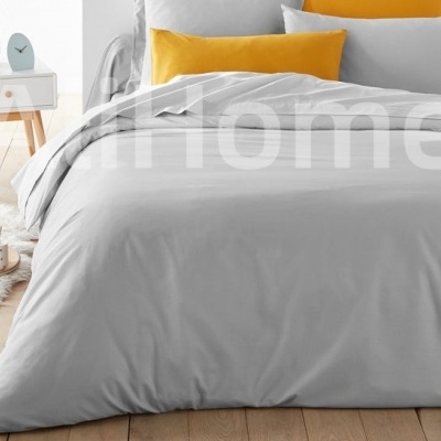 Cama com edredão cinzento claro e almofadas amarelas e cinzentas num quarto moderno