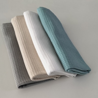 Quatro panos de cozinha dobrados em cores diferentes com textura quadriculada.