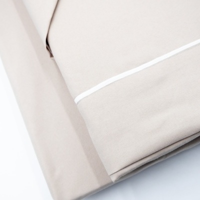 Lençóis de cama bege claro com detalhe branco