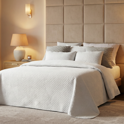 Quarto com cama de casal, cabeceira estofada e roupa de cama texturada branca.