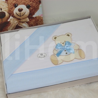 Cobertor branco e azul com urso azul em caixa sobre superfície felpuda