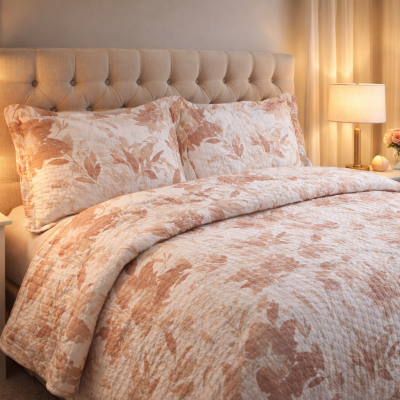 Conjunto de cama com edredão e almofadas florais e cabeceira estofada numa sala iluminada