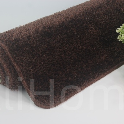 Tapete castanho enrolado ao lado de vaso dourado com plantas