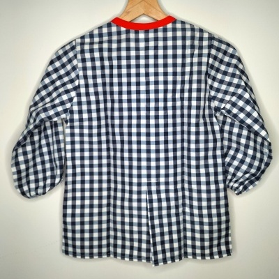 Blusa xadrez azul e branca com gola vermelha pendurada num cabide