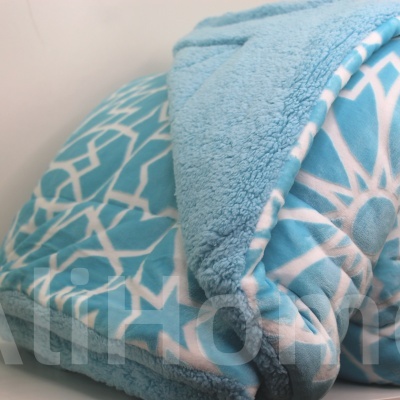 Manta azul claro com padrão geométrico branco dobrada