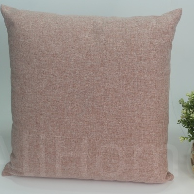 Almofada rosa texturizada ao lado de planta em vaso dourado