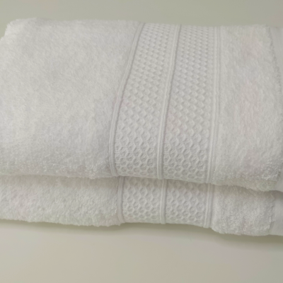 Toalhas de banho brancas empilhadas com faixa decorativa em relevo