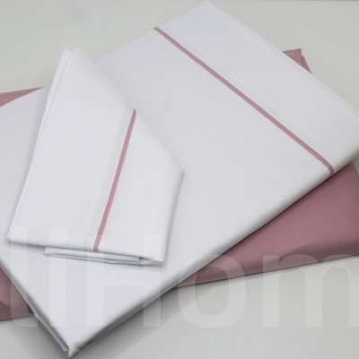 Conjunto de roupa de cama branco e rosa com planta ao lado