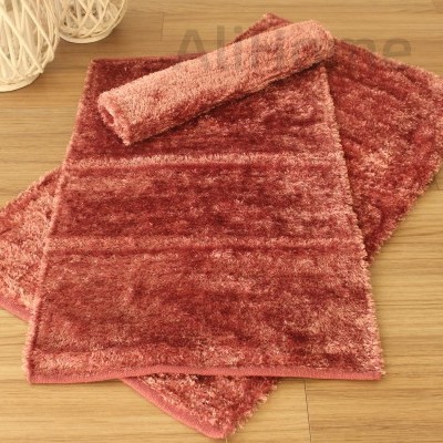 Tapete felpudo vermelho e rosa sobre chão de madeira clara com decoração branca ao fundo