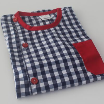 Camisa xadrez azul e branca com detalhes vermelhos dobrada sobre superfície branca