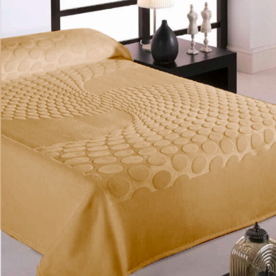 Colcha mostarda com padrão circular em relevo numa cama com mesa de cabeceira e decoração ao fundo