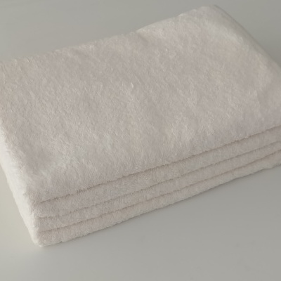 Toalha branca felpuda dobrada sobre superfície branca