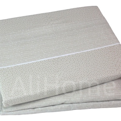 Lençol algodão com padrão de círculos bege e branco dobrado