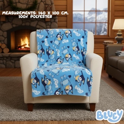 Manta azul decorada com cão Bluey numa poltrona clara junto a uma lareira acesa