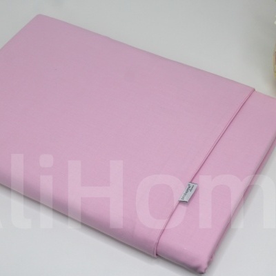 Lençol cor-de-rosa dobrado com vaso decorativo ao lado