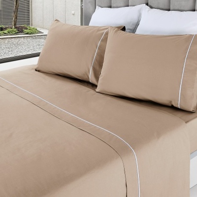 Cama com lençóis bege com risca branca fina e fronha, cabeceira cinza e janela para jardim