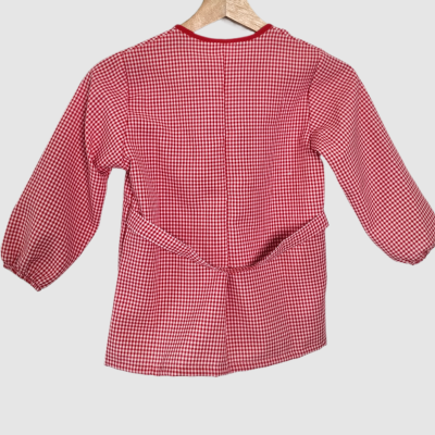 Casaco infantil xadrez vermelho e branco de manga comprida pendurado num cabide.