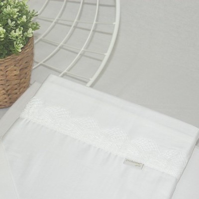 Lençol branco com bordado em renda floral ao lado de planta em vaso de vime