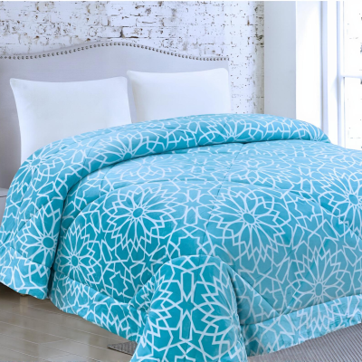 Edredão azul claro com padrão geométrico branco numa cama com almofadas brancas e mesa de cabeceira