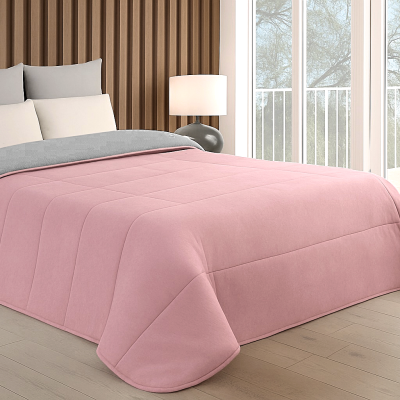 Cobertor reversível cinza e rosa em cama moderna com almofadas cinza e branco em quarto com cabeceira de madeira e piso claro