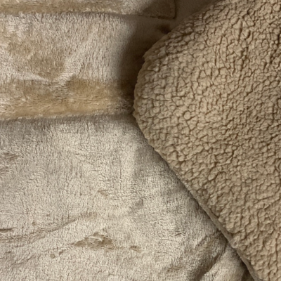 Cobertor ou manta dupla face bege com textura lisa e textura felpuda.